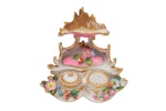 Tinteiro de  porcelana Velho Paris em branco, ouro, rosa, com florzinhas policromadas em relevo, no estilo neo-rococó. Tem recipiente para tinta, polvilhador e porta penas. França - Século XIX. Med.  14 x 16 x 9 cm (ME). Marcas e desgastes do tempo . Presença de antigo restauro e dois trincos na parte inferior da base. Acervo Particular Rio de Janeiro/RJ.