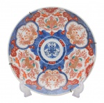 Arte Oriental - Belíssimo prato de porcelana japonesa dita "imari", profusamente decorado, em sua policromia característica, pelos esmaltes nas cores azul índigo, vermelho e "rouge de fer" sobre fundo branco, reproduzindo as temáticas floral e grafismos. Japão -Séc. XX. Med. 32cm (ME). Marcas do tempo. Acervo Particular Rio de Janeiro/RJ.