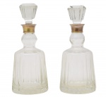 Baccarat - Elegante par de garrafas de grosso cristal, manufatura atribuída a famosa cristaleria Baccarat, finamente lapidadas, na cor hiálico. Ambas guarnecidas por gargalo de metal com inscrições ilegíveis.   França - Séc. XX. Med 31 x 11 cm de diâmetro. Marcas de uso. Uma delas está com fungos e  trincado na parte interna do gargalo.  Acervo Particular Rio de Janeiro/RJ. Nota: A Baccarat é uma das mais prestigiadas fabricantes de cristal do mundo. Fundada em 1764, na cidade de Baccarat, na região de Lorraine, França, por ordem do rei Luís XV, ela rapidamente se tornou sinônimo de luxo, requinte e excelência artesanal. Se destaca por seu cristal de altíssima qualidade, conhecido por sua pureza, brilho e precisão nos cortes, e por produzir peças de decoração, iluminação, jóias, taças, copos, vasos, candelabros, entre outros. com um currículo irrepreensível ,Já forneceu cristais para famílias reais, chefes de estado e luxuosas casas europeias e trabalhou com grandes designers e artistas, sendo símbolo da arte de viver francesa. Existe um Museu Baccarat em Paris e também um na sede original, na cidade de Baccarat.Lindo par de garrafas de grosso cristal, manufatura atribuída a famosa cristaleria Baccarat., finamente lapidadas, na cor hiálico. Med 34 cm de altura. Marcas de uso. Uma apresenta pequenos bicados na borda e no interior da tampa. A outra borda do "gargalo" faltas e perda de substância. Presença de fungos no interor de uma delas. No estado.