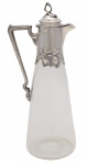 Art Nouveau -  Belíssimo "Claret Jug" de cristal europeu com guarnição de prata alemã fundida, estilo e época Art Nouveau. Marca de contraste Alemanha - Século XIX.  Marca de ourives ilegível. Med 35 x 15 x 11 cm (medidas totais). Marcas de uso. Peça de coleção. Acervo Particular Rio de Janeiro/RJ. Nota: História e Origem do dos Claret Jug - O nome "Claret" tem origem francesa e significa "brilhante" ou "claro" e refere-se a um vinho francês brilhante de Bordéus. No século 18, floresceu uma ampla produção de garrafas de galheteiro montadas em prata. Eles tinham tamanhos de 15-18 cm, mas nenhuma garrafa mais alta ou maior adequada para servir vinho foi fabricada! Os primeiros exemplos de garrafas de "vinho" foram feitos na década de 1830 e entre os primeiros estavam as fabricadas em Londres pela Reilly & Storer. Embora o vidro tenha sido usado para recipientes de bebida desde os primeiros tempos, apenas o século 19 viu o desenvolvimento do "Jarro Claret". Os ourives começaram a "modificar" os decantadores de vidro usados no século 18 pela adição de faixas simples de prata e substituindo as rolhas de vidro por tampas com dobradiças de prata. No segundo quartel do século, foram acrescentados cabos de prata e suportes maiores, embora, na maioria dos casos, o vidro mantivesse a forma de "garrafa" e design contido.