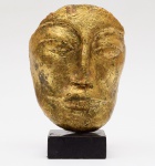 ESCULTURA em cerâmica, moldada no formato de máscara e realçada em esmaltes dourados. Assinada com monograma no verso. Base retangular preta. Med. Alt. 22,0 cm.