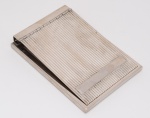 PREDENDOR retangular para bloco de folhas de papel, em metal prateado com capa reclinável ornamentada por filetes. Base de tamanho um pouco maior, seguindo o estilo. Med.  Compr. 15,0 cm   Larg. 10,5 cm.