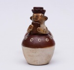 ESCULTURA - "Huaco silbador", em cerâmica moldada com dois vasos, realçado por pigmento marrom e decorado com motivos geométricos. Apresenta figura em relevo segurando flauta, acoplada a vaso com gargalo reto. Peça contemporânea no estilo da arte pré- colombiana. Deve o seu nome ao fato que, enchendo o vaso com água e movimentando os vasos alternadamente de cima para baixo, se obtém um assovio produzido pela passagem do líquido de um recipiente para o outro. Medidas: Alt. 16,0 cm Compr. 20,0 cm.