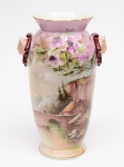 ANTIGO VASO em porcelana europeia, de formatolevemente ovalado, decorado em policromia sobre fundo cor de rosa.Frente apresentando paisagem alpina encimada por composiçãofloral, e verso com flores do campo. Bojo ladeado por medalhõesmoldados em relevo com cabeças femininas. Gargalo baixo emcorneta, com borda lobulada e dourada. Base circular, lisa eesparramada. Med. Alt. 35,0 cm.