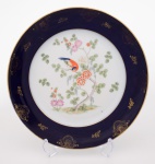ROSENTHAL - SELB  - Antigo prato em porcelana alemã policromada, com margem azul noturno realçada por filete e adornosdourados. Centro apresentando pássaro pousado em árvore florida.Marca da manufatura no verso. Med. Diâm. 28,0 cm
