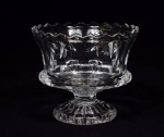FRUTEIRA circular em cristal com pé e borda dentada. Bojo abaulado, com laterais arqueadas, lapidadas e ornadas por facetas amendoadas. Haste curta e chanfrada, apoiada em baselavrada em gomos. Med. Alt. 18,5 cm.  Diâm. 21,0 cm.