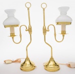 PAR DE LUMINÁRIAS de mesa em metal dourado, construídas no formato de antigos lampiões. Bases circulares cônicas, encimadas por hastes tubulares recurvas e rematadas ao topo por pegas em argolas. Apresentam à meia altura adornos ovalados, sustentando braços em S encimados por bobeches com velas. Cúpulas em vidro leitoso, moldadas em corneta com anelados retraídos ao centro. OBS: Perfeito estado. Med. Alt, 49,0 cm  Larg. 19.0 cm.