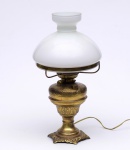BELO LAMPIÃO adaptado para luz elétrica em bronze polido e metal dourado, lavrado com estilizações florais. Bojo cônico, encimado por queimador e sistema de regulagem da chama, apoiado em haste anelada. Cúpula em vidro opalinado leitoso, encimado por pequeno gargalo em corneta. Base recortada e lavrada com adornos em relevo. OBS: Metal apresenta poucas oxidações, necesitando de limpeza específica. Med. Alt. 50,0 cm.