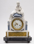 RELOGIO DE MESA FRANCÊS - Belo relógio francês com caixa retangular chanfrada, em biscuit branco e azul, ornada por adornos em bronze dourado. Apresenta segmento central ladeado por colunatas, centralizando mostrador com marcação À Paris e moldura oitavada.Topo com figura materna cuidando de gêmeos recém-nascidos deitados em cesta. Base saliente com frente realçada por placa lavrada com anjos musicistas. Base em mármore preto apoiada em pequenos pés retos.  França Século XIX. Med. Alt. 43,0 cm  Compr. 30,0 cm  Prof. 12,0 cm.