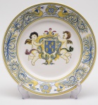 FAIANÇA DE COIMBRA PORTUGAL - Medalhão em faiança decorado com brasão apresentando escudo azul com cinco flores de liz amarelas, ladeado por dois querubins e encimado por uma coroa. Med. Diâm. 34,5 cm