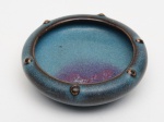 PEQUENA TIJELA lava-pinceis para mesa de letrado, emporcelana chinesa com coberta monocromática celadon azul do tipo Jun commancha escorrida em tons magenta. Bojo circular achatado, com bordarealçada por pequenas tachas em relevo e base retraída. Peça de coleção.Dinastia Song (960-1279).  Med. 2.5 cm x7.7 cm x 7.7 cm.
