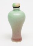 SNUFF BOTTLE de formato balaústre, em porcelanachinesa revestida por coberta em tonalidades degradês verde água epeachbloom. Tampa com cabochão em jade branco rajado com verde, colarpreto e colher. Séc. XIX.