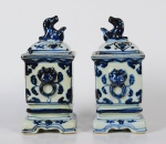 PAR DE INCENSÓRIOS quadrangulares em porcelana chinesa, apresentando decoração floral em azul cobalto. Bojos retos ladeados por pegas moldadas com cabeças de leão e argolas. Tampas abobadas com pegas no formato de Cão de Fó. Bases recortadas com pés retos. Século XIX. Medidas: Alt 19,0 cm, 9,0 cm e 9,0 cm.
