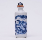 SNUFF BOTTLE chinesa de formato cilíndrico em porcelana chinesa, decorada em azul com meninos jogando Go. Assinada no verso do bojo. Marca sob a base. Tampa em porcelanaazul, com colar de cor coral e colher. Séc. XIX. Med. Alt. 9,0 cm