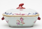 CIA. DAS ÍNDIAS - Pequena terrina para molho, de formato retangular chanfrado, em porcelana chinesa da Companhia das Índias, decorada em esmaltes policromados da Família Rosa. Apresenta decoração floral realçada por borda em volutas. Bojo reto, ladeado por alças no feitio de cabeças de javali. Tampa levemente abobadada encimada por pega com adorno vegetal. Reinado Qianlong (1736-1795). (Mínimos restauros na borda). Med. Alt.10,0 cm Larg. 18,0 cm  Prof. 13,0 cm.