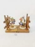 2 ESCULTURAS EM PORCELANA ALEMÃ M.J HUMMEL REPRESENTANDO CRIANÇAS EM ÁRVORE  AMBAS PEÇAS COM AVARIA. NA BASE DE MADEIRA  MEDIDA: 13 CM DE ALTURA X BASE 10 CM X 9 CM DE LARGURA