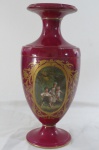 Imponente vaso de porcelana na tonalidade grená, possivelmente Sevrés, com rica e farta esmaltagem representando crianças à frente e flores no verso; detalhes em ouro. França Séc. XIX. Alt. 55cm.