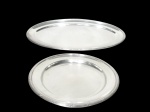 <b>FRACALANZA</b>, duas (2) travessas, sendo: A) 1 grande travessa oval, medindo 68x37,5cm e B) 1 travessa redonda, medindo 36cm de diâmetro, confeccionadas em metal espessurado a prata, borda cinzelada por caneluras e fitas cruzadas.