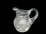 <b>CRISTAL</b>, um (1) pequena jarra confeccionado em cristal translucido ricamente lapidada por cata ventos, estrelas e caneluras em baixo relevo, medindo 9x9x5cm.