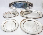 Elegante baixela de 5 peças, executadas em metal espessurado á prata de ótima qualidade e fundição, design exclusivo. Bom estado de conservação. Bandeja maior oval mede 55 x 21 cm. Redonda maior 36,0 cm de diâmetro.