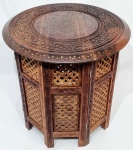 ÍNDIA - Belíssima e clássica mesa Indiana, finamente construída a mão em pesada e antiga madeira típica de lei, ricamente decorada com belíssima ornamentação floral, incrustação de metal dourado e riquíssimo acabamento fenestrado. Índia, meados do Século XX. Excelente estado de conservação. Mede 46,0 cm de altura x 46,0 cm de diâmetro do tampo.