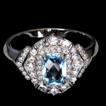Belíssimo anel em prata de lei espessurada a ouro branco, design exclusivo de excepcional ourivesaria com precioso Topázio Sky Blue de 7.0 x 5.0 mm, clássica lapidação almofada brilhante, adornado por rico trabalho e majestosas coroas de Zirconias de lapidações princess e diamante. Perfeito estado de conservação, sem uso. Aro mede 1,9 cm, armação 1,6 x 1,4 cm. Origem África.
