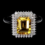 Belo anel em prata de lei espessurada a ouro branco, design exclusivo de excepcional ourivesaria com precioso Citrino extra de 9.0 x 7.0 mm, clássica lapidação esmeralda brilhante, adornado por rico trabalho, fino acabamento e majestosas coroas de Zirconias extra brancas. Perfeito estado de conservação, sem uso. Aro mede 1,8 cm, armação 1,2 x 1,4 cm. Origem África. OBS: FORMA CONJUNTO COM O LOTE Nº