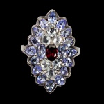 MAGNIFICO ANEL EM PRATA DE LEI ESPESSURADA A OURO BRANCO, DESIGN MODERNO EXCLUSIVO DE EXCEPCIONAL OURIVESARIA COM PRECIOSA GRANADA RODOLITA DE 6.0 X 4.0 MM, CLÁSSICA LAPIDAÇÃO OVAL BRILHANTE, ADORNADA POR RICO TRABALHO E FINO ACABAMENTO COM BELÍSSIMAS COROAS DE ÁGUAS MARINHAS E TANZANITAS DE 4.0 X 3.0 MM LAPIDAÇÕES OVAL E GOTA BRILHANTE. PERFEITO ESTADO DE CONSERVAÇÃO, SEM USO. ARO MEDE 1,9 CM, ARMAÇÃO 2,8 X 1,8 CM . ORIGEM MOÇAMBIQUE, BRASIL E TANZÂNIA.