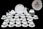 ROYAL KENT COLLECTION, GRÃ BRETANHA - GEORGE V - BRASÃO DA COROA - Elegantíssimo e tradicional aparelho de chá, café e sobremesa. Peças executadas finamente em porcelana de excepcional qualidade e manufatura, adornadas por brasão central com coroa e monogramas em vibrante azul cobalto, bordas delicadamente onduladas em relevo e riquíssimos filetes á ouro nas bordas. Típico da estética aristocrática inglesa. Composto por: 10 xícaras para café e 10 para chá com seus respectivos pires, 10 pratos rasos para sobremesa, 01 prato raso de serviço, 01 bule, 01 chaleira, 01 cremeira com presentoir, 01 leiteira e 01 açucareiro. Perfeito estado de conservação. Reino Unido, meados do Século XX.