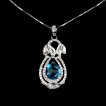 Majestoso colar em prata de lei espessurada a ouro branco, design exclusivo de excepcional ourivesaria. Pingente com precioso Topázio London Blue extra de 12 x 8.0 mm, clássica lapidação pera brilhante, adornado por rico trabalho, fino acabamento e majestosa coroa de Topázios extra brancos de lapidação brilhante. Perfeito estado de conservação, sem uso. Corrente com clássica malha veneziana, mede 45 cm, pingente 3,5 x 1,5 cm. Origem África e Brasil.