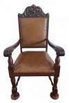 Imponente e clássica poltrona em estilo neorrenascentista, construída em madeira nobre ricamente entalhada, espaldar alto com decoração floral e volutas, braços curvos com entalhes, pernas torneadas com travessas e pés em formato de concha, assento e encosto estofados em courvin marrom com acabamento em tachas. Bom estado de conservação, mede 115,0 cm de altura x 65,0 cm de largura x 59,0 cm de profundidade.
