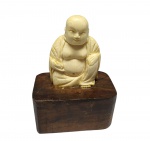 ESCULTURA EM MARFIM DE EXCELENTE QUALIDADE ESCULTÓRICA REPRESENTANDO BUDA SENTADO, ASSENTE SOBRE BASE DE MADEIRA. CHINA SÉC XX. PERFEITO ESTADO DE CONSERVAÇÃO. MEDE APROX 8,5 X 6,0 CM.