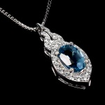 Elegante colar em prata de lei espessurada a ouro branco, design exclusivo de excepcional ourivesaria. Pingente com belo Topázio London blue extra de 6.0 x 4.0 mm, clássica lapidação oval brilhante, adornado por rico trabalho e fino acabamento com majestosa coroa de Zirconias extra brancas. Perfeito estado de conservação, sem uso. Corrente com clássica malha veneziana, mede 45 cm, pingente 1,6 x 0,6 cm. Origem África.