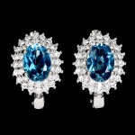 Clássico e elegante par de brincos em prata de lei espessurada a ouro branco, design exclusivo de excepcional ourivesaria com belíssimo Topázio London blue de 7.0 x 5.0 mm, clássica lapidação oval brilhante, adornado por rico trabalho, fino acabamento e majestosas coroas de Zirconias extra brancas de lapidação brilhante. Perfeito estado de conservação, sem uso. Medem 1,2 x 1,0 cm. Origem África.