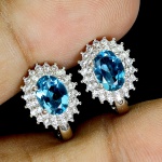 Clássico e elegante par de brincos em prata de lei espessurada a ouro branco, design exclusivo de excepcional ourivesaria com belíssimo Topázio London blue de 7.0 x 5.0 mm, clássica lapidação oval brilhante, adornado por rico trabalho, fino acabamento e majestosas coroas de Zirconias extra brancas de lapidação brilhante. Perfeito estado de conservação, sem uso. Medem 1,2 x 1,0 cm. Origem África.