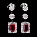 Elegante par de brincos em prata de lei espessurada a ouro branco, design exclusivo de excepcional ourivesaria com belíssimo Rubi de 6.0 x 4.0 mm, clássica lapidação esmeralda brilhante, adornado por rico trabalho floral com Zirconias e fino acabamento com majestosa coroa de Zirconias extra brancas. Perfeito estado de conservação, sem uso. Medem 2,2 x 0,8 cm. Origem África.