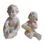 Duas esculturas em biscuit representando crianças, o pano que cobre a perna da menina está quebrado na lateral, 10 e 9 cm. Alt.