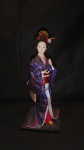 COLECIONISMO - Linda Gueixa japonesa em traje típico de tecido azul e dourado, sobre base de madeira. med. 31cm