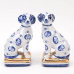 Par de esculturas em porcelana chinesa, nas cores azul e branco com motivos florais e douração representando Cachorros, altura 20 cm.