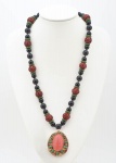 LUCIEN FINKELSTEIN - Extraordinário colar com pendentif, construído por elegante colar com esferas em ônix, coral esculpido e esferas em jade, sustentando um pendentif em ouro 18 k, assinado LUCIEN, esmaltado, com 40 diamantes lapidados, e brilhante encimado, esferas de jade e pedra central coral em forma de gota, medida do cordão 39 cm de comprimento e medida do pendentif 5 x 4,5 cm.
