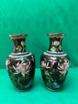 Pares vasos chineses cloisonné, início do século XX.A técnica cloisonné envolve a aplicação de esmalte em compartimentos metálicos totalmente artesanal, criando padrões decorativos. Esses vasos específicos apresentam um fundo preto com desenhos florais coloridos, incluindo crisântemos, e detalhes em azul claro e dourado nas bordas.A arte cloisonné é uma tradição antiga, com origens que remontam ao século XIV na China. Como se encontram nas fotos medindo 25 cm de altura por 8 cm de diâmetro.
