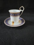 Xicara de café, com um design elegante, A decoração apresenta um design intrincado em porcelana fina, com detalhes em azul e dourado. A xícara possui três pés dourados e uma alça estilizada com detalhes dourados. A borda da xícara e do pires é adornada com uma faixa azul e dourada com um padrão floral. Abaixo dessa faixa, há uma área branca lisa, seguida por outra faixa com um padrão floral mais detalhado em azul e dourado. Em bom estado como se pode ver nas fotos. 