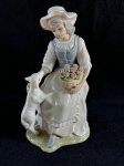 Tengra.Belíssima escultura de fina porcelana espanhola, Tengra, representando uma camponesa com um cordeiro e uma cesta de rosas, peça, identificada como "Tengra Girl with Lamb".Esta escultura retrata uma jovem camponesa vestida com um vestido branco, avental azul e chapéu, segurando uma cesta com rosas cor-de-rosa. Um cordeiro branco está ao seu lado, encostando-se à sua perna. A base da estatueta simula um terreno gramado.Em bom estado de conservação, como se pode observar nas fotos medindo 26 cm de altura por 14 cm der largura.   