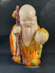 Deus FUKUROKUJU Belíssima escultura em fina porcelana policromada, início século XX, representando o Deus FUKUROKUJU, segundo o Xintoísmo, Mitologia e Folclore japonês, Deus da longevidade e sabedoria, representado por uma longa barba branca trazendo na mão um cetro ou bastão (saku) sagrado e um pêssego.Ter sua estatueta traz popularidade e garante longevidade.Conforme nas fotos medindo 27 cm de altura. 