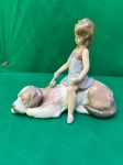 Lladró.Belíssima escultura em fina porcelana da Lladró, intitulada "Contented Companion" (Companheiro Contente). A peça retrata uma menina escovando um cão São Bernardo deitado. Criada pelo escultor Juan Huerta, foi lançada em 1995 e retirada em 2001.Bom estado como se pode visualizar nas fotos. Medidas: 16 cm de comprimento por 14 cm de altura. 