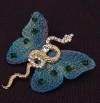 Belíssimo Broche , representando Borboleta envolvido por uma cobra , trabalhados em pedra e as assas da borboleta revestido em tecido furta cor e pedrinhas . Medindo : 5 x 5 cm
