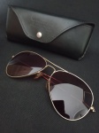 Óculos estilo Ray ban , com armação dourada .