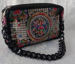Bolsa bordada em policromia com flores, arabescos e formas geométricas; alça na cor preta em material sintético . Medindo 30x22x6  cm.