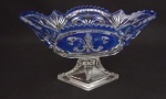 Fruteira/centro de mesa em cristal  na cor azul , borda recortada e serrilhada , em forma de naveta , decorado com lapidação de flor de liz , apoiado sobre base facetada . Medida : 25 x 13 x 14 cm .