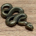 Miniatura representando cobra, feito em cobre, rico em detalhes. Medidas: Altura 0,3 cm x Largura 2,5 cm x Profundidade 4 cm.